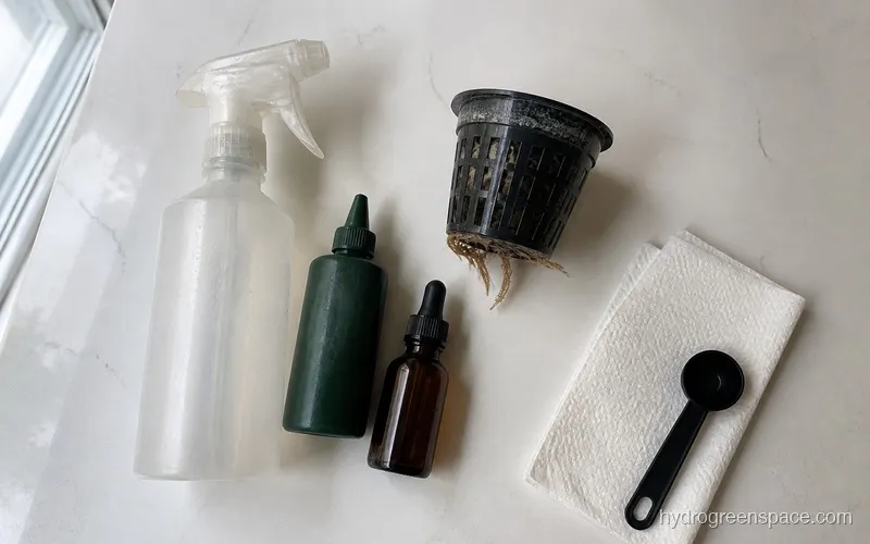 A spray bottle, small dish soap bottle, and neem oil bottle arranged next to a hydroponic net pot